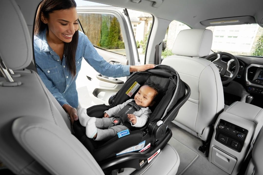 Mother adjusting infant riding in Graco SnugRide SnugLock infant car seat