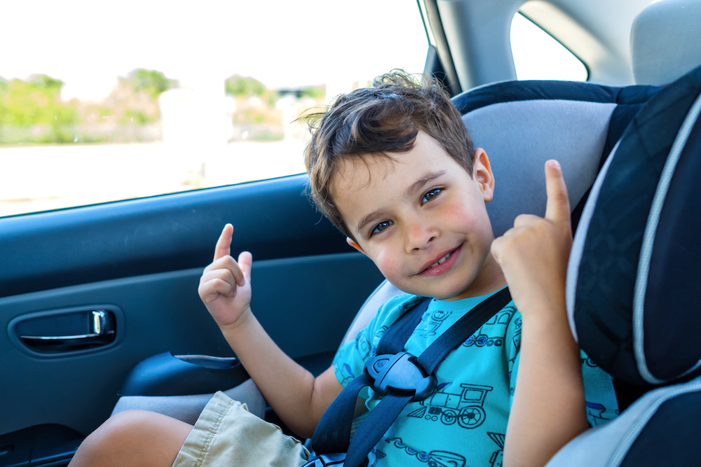 Young boy in blue shirt sitting in forward facing car seat