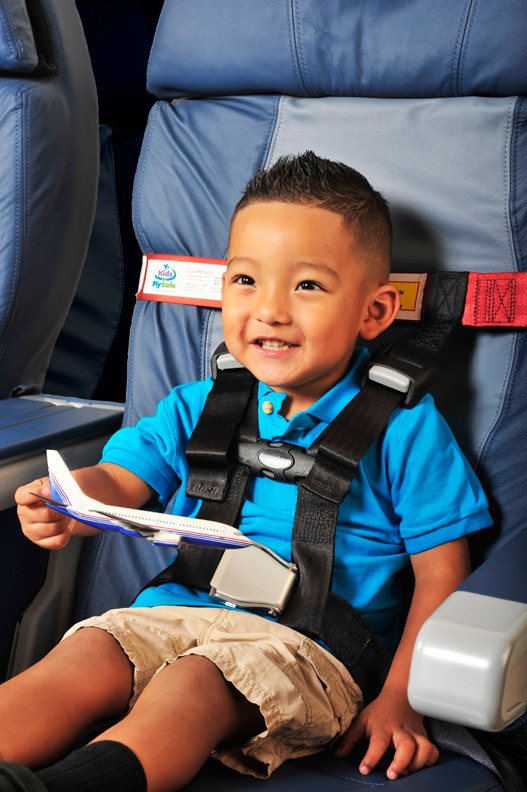 Young boy in blue shirt holding toy airplane while secured in the AmSafe CARES child restraint