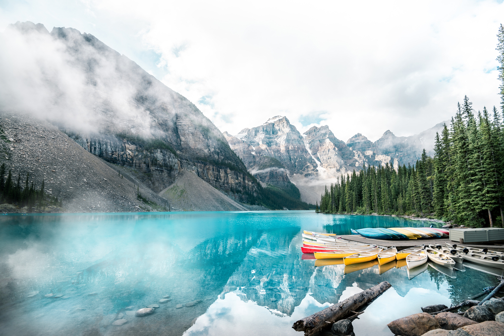 Travel Car Seat Expert - Canoes on a lake with mountains in the background, perfect for a peaceful retreat or adventurous exploration.