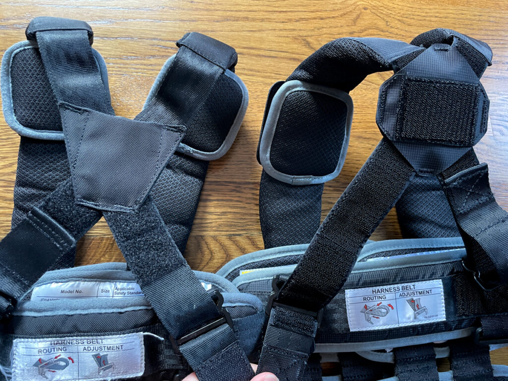 Travel Car Seat Expert - Two black harnesses on a wooden table.