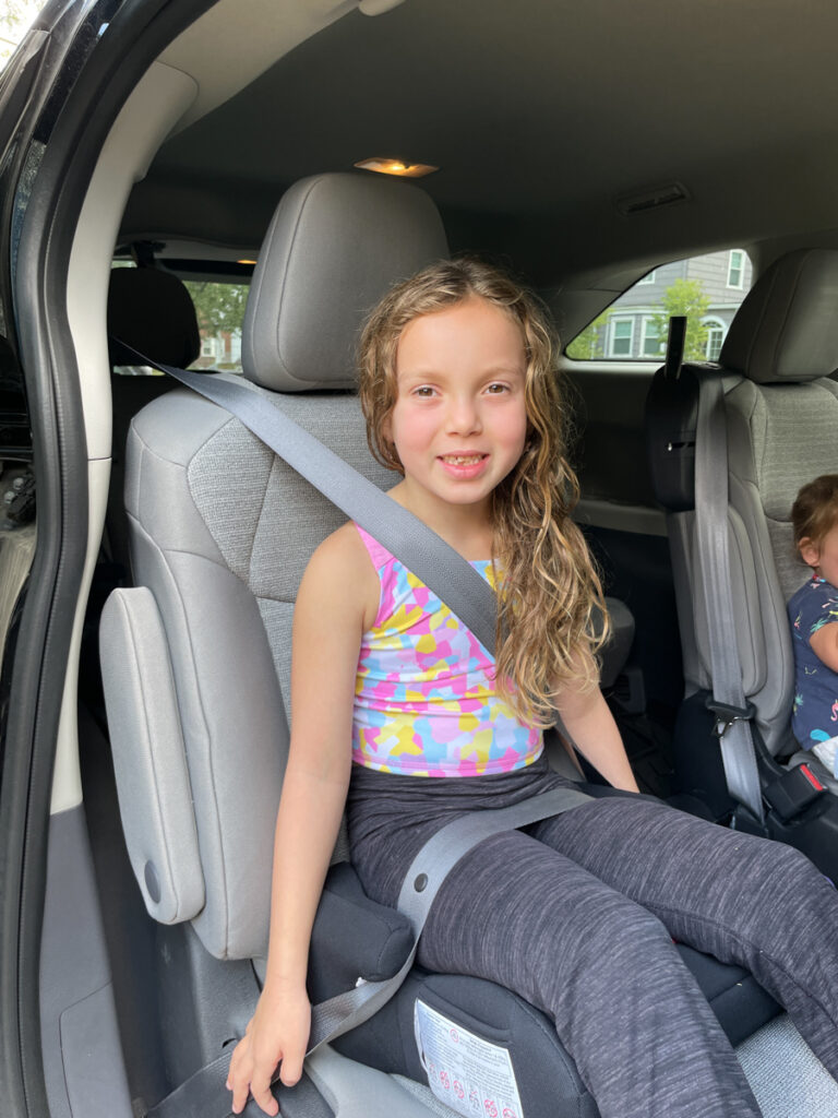 Travel Car Seat Expert - A little girl sits in the back seat of a car.