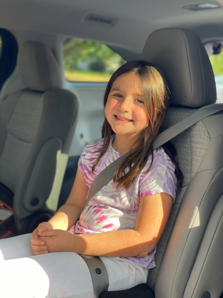 Travel Car Seat Expert - A young girl sitting in the back seat of a car.