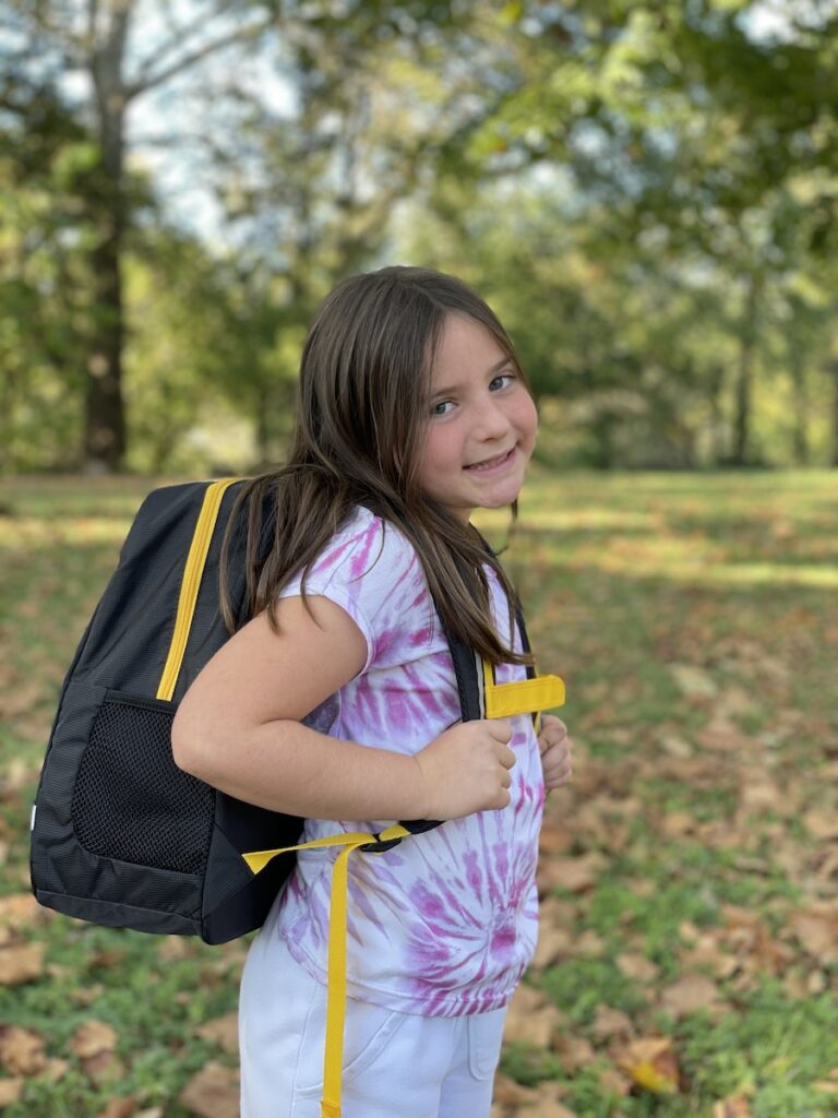 Travel Car Seat Expert - A young girl wearing a black and yellow backpack.