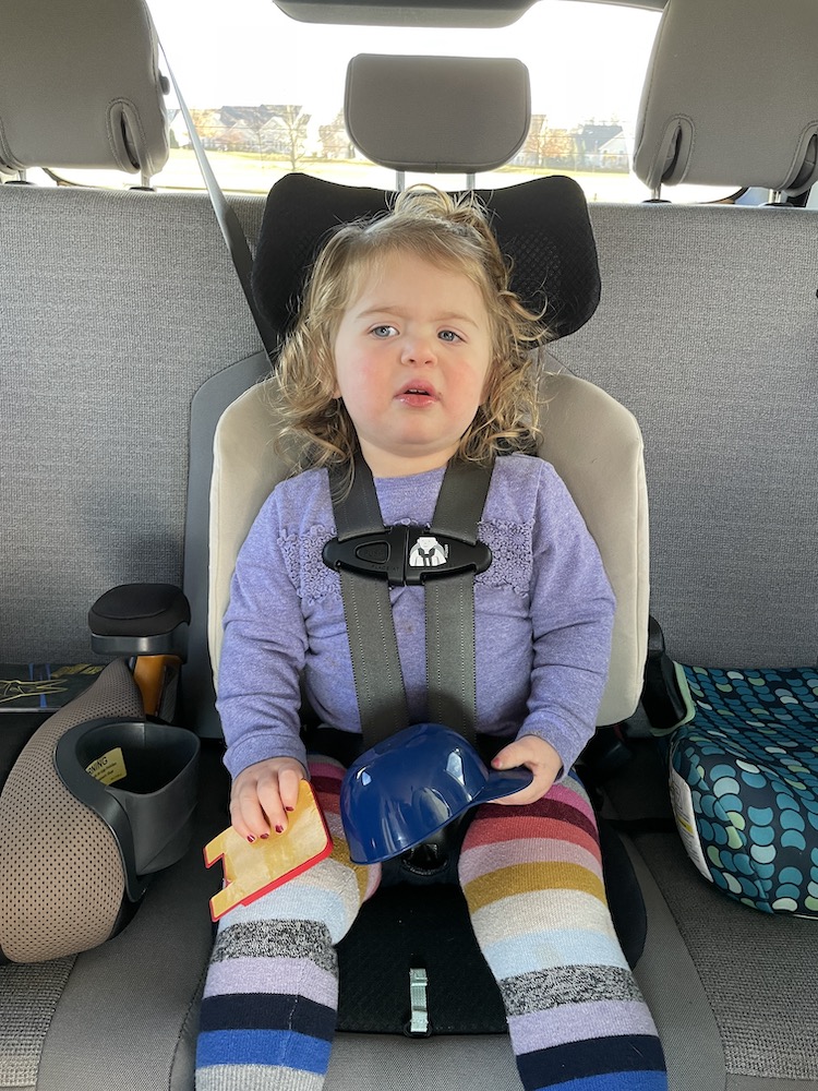 Travel Car Seat Expert - A little girl sitting in a car seat holding a toy, using the best travel car seat for a 2 year old.