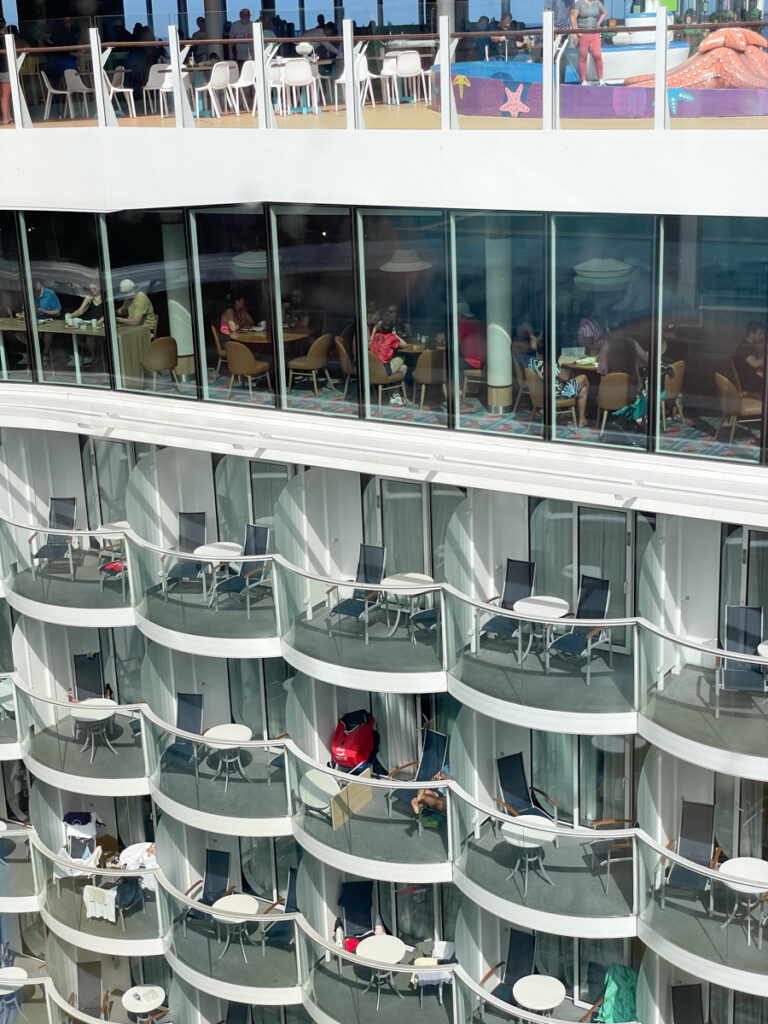 Travel Car Seat Expert - A glimpse of cruise ship balconies overlooks a lively dining area where passengers, considering what you need to know about cruising, enjoy their meals.